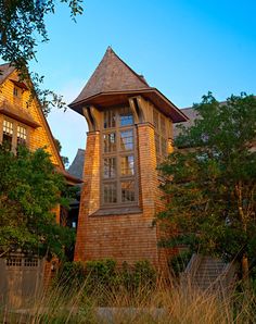 a tall wooden clock tower sitting in the middle of a lush green field next to trees