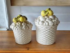 two white ceramic containers sitting on top of a wooden table