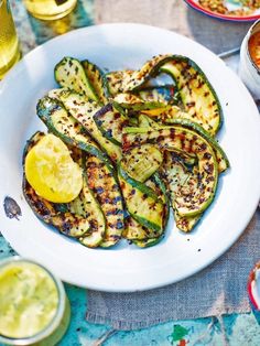 grilled zucchini on a white plate with lemon wedges next to it