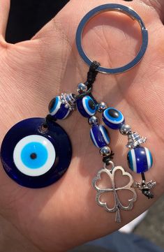 a hand holding a keychain with an evil eye on it