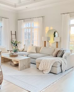 a living room filled with white furniture and lots of window sill space in front of the couch