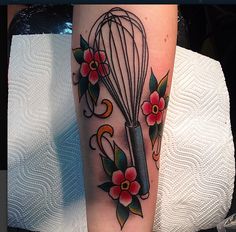 a tattoo on the arm of a woman with a whisk and flowers