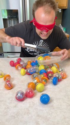 a man in blindfolded eye glasses cutting up candy balls on a kitchen counter