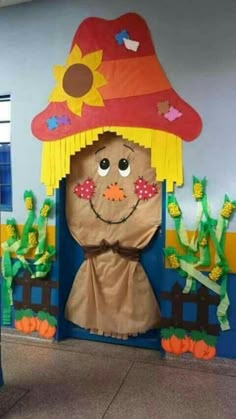 a cardboard scarecrow with a red hat on it's head, and other decorations around him