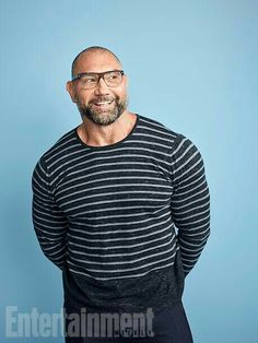 a man with glasses and a striped shirt is standing in front of a blue background