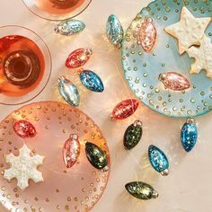 three plates and two wine glasses on a table with christmas decorations around them, including star shaped cookies