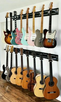 guitars are lined up on the wall and hanging from hooks in a music room or studio