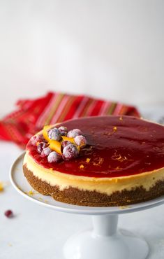 a cheesecake with cranberry topping on a white cake stand