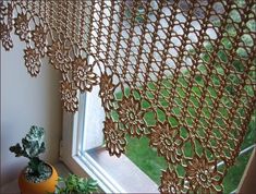 a window covered in gold lace next to a potted plant