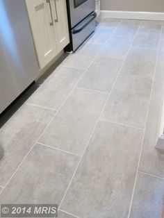 a kitchen with gray tile flooring and stainless steel appliances