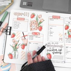 a person holding a pen in their hand next to an open planner book with various things on it