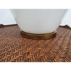 a white lamp sitting on top of a woven table cloth next to a wooden base