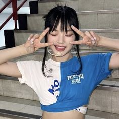 a woman with her hands in front of her face making the peace sign while standing on some stairs