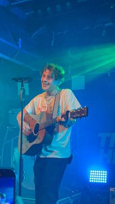 a young man holding a guitar on stage