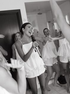 a group of women standing around each other in front of a mirror holding microphones