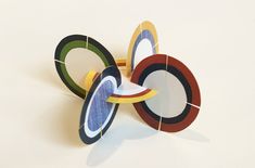 an abstract sculpture made out of colored circles on a white surface, with one circular in the center