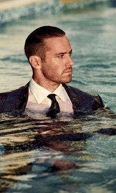 a man wearing a suit and tie swimming in the water with his head turned to the side