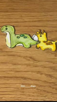 two cartoon animals are laying down on the wood floor, one is green and the other is yellow