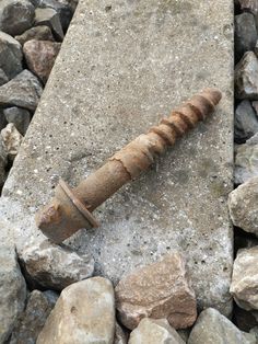 an old rusty screw laying on some rocks