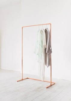 an open clothes rack with two shirts hanging on it's sides, in front of a white wall