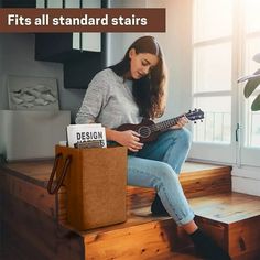 a woman sitting on the steps playing an acoustic guitar and looking down at her book