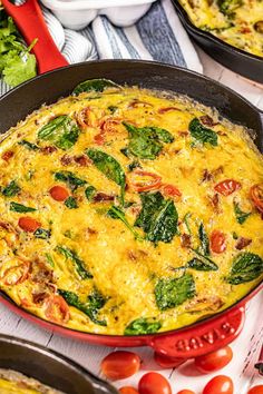 an omelet with spinach and tomatoes in a skillet on a table