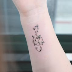 a small tattoo on the wrist of a woman's arm that has flowers growing out of it