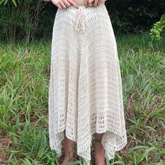 a woman standing in the grass with her hands on her hips, wearing a white crochet skirt