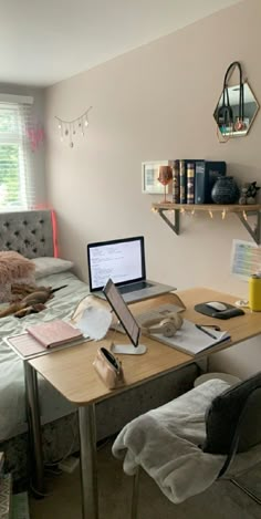 a laptop computer sitting on top of a wooden desk next to a bed in a bedroom