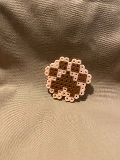 a brown and white brooch sitting on top of a tan cloth covered ground with an object in the middle