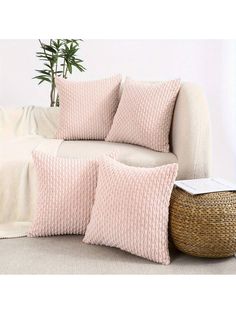 a white couch sitting next to a basket on top of a floor