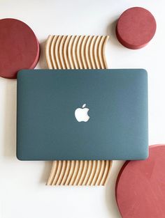 an apple laptop sitting on top of a white table next to red circles and wooden discs