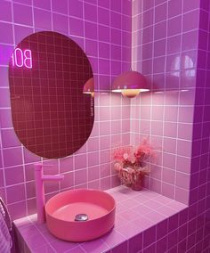 a bathroom with pink tiles and a round mirror