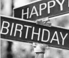 black and white photograph of two street signs with the words happy birthday written on them