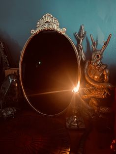 a mirror sitting on top of a wooden table next to a small statue and candle