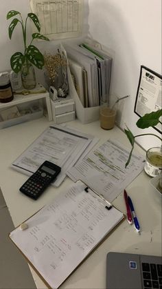 a laptop computer sitting on top of a desk next to papers and a calculator