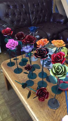 many different colored roses are placed on a table in front of a black leather couch