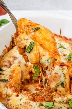 someone is taking a piece of lasagna out of the casserole dish