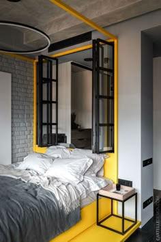 a bed with white and yellow sheets in a bedroom next to a mirror on the wall