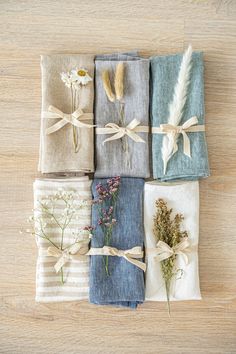 four folded napkins with flowers tied to them on a wooden table next to each other