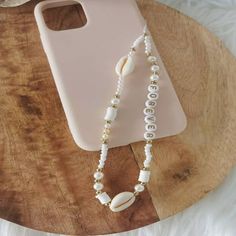 a cell phone case with pearls and a shell on it sitting on a wooden table