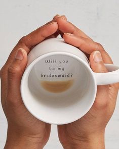 two hands holding a coffee cup with the words will you be my bridesmaid?