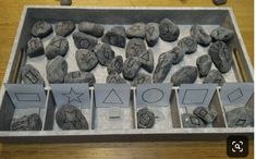 rocks and shapes are arranged in a tray on a table next to colored crayons