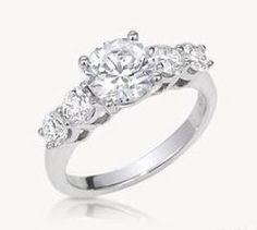 a three stone engagement ring with diamonds on the shoulders and side stones in white gold