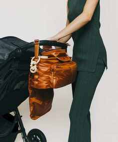 a woman holding a brown bag next to a stroller