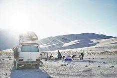 a van is parked in the desert with people around it