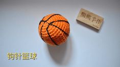 an orange crocheted basketball sitting on top of a table next to a rubber stamp