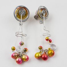 Those impressive 1990s Space Age oversized aluminum dangling clip-on earrings feature a stunning hand-made futuristic design with a dangle articulated spiral coil and geometric elements along with assorted size beads. The iridescent hot pink and yellow-orange color beads embellish the silver metal framing. There is no visible maker's mark. Measurements: 1.19 in wide (3 cm) x 4.57 in long (11.6 cm).  Please see the measurements noted above in the description for the best approximate dimensions. Space Age Jewelry, Futurism Jewelry, 50s Futurism, Alien Jewelry, Geometric Elements, Color Beads, Futuristic Design, Maker's Mark, Accessories Jewelry Earrings