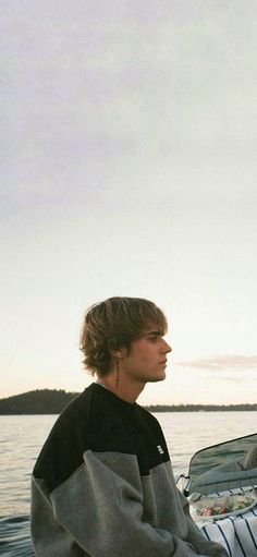 a young man sitting on top of a boat in the water