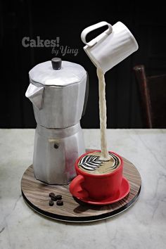 a coffee maker pouring milk into a red cup on top of a wooden coaster with white napkins